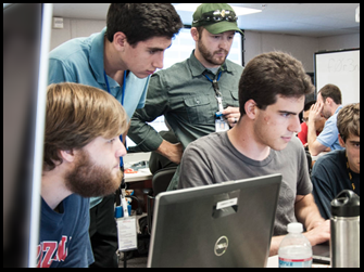 Several interns look at a computer monitor.